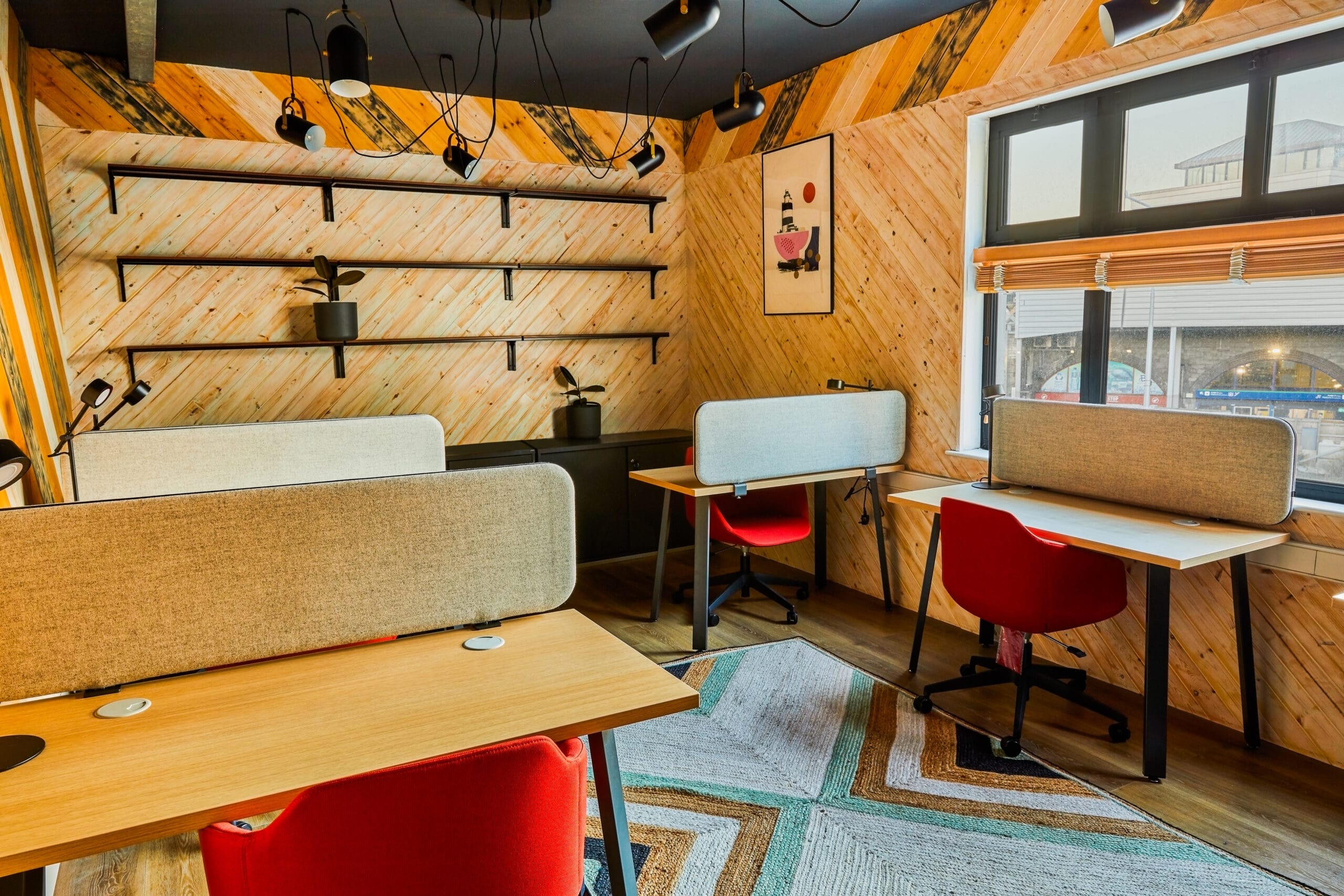 Cozy modern workspace with desks and red chairs by window