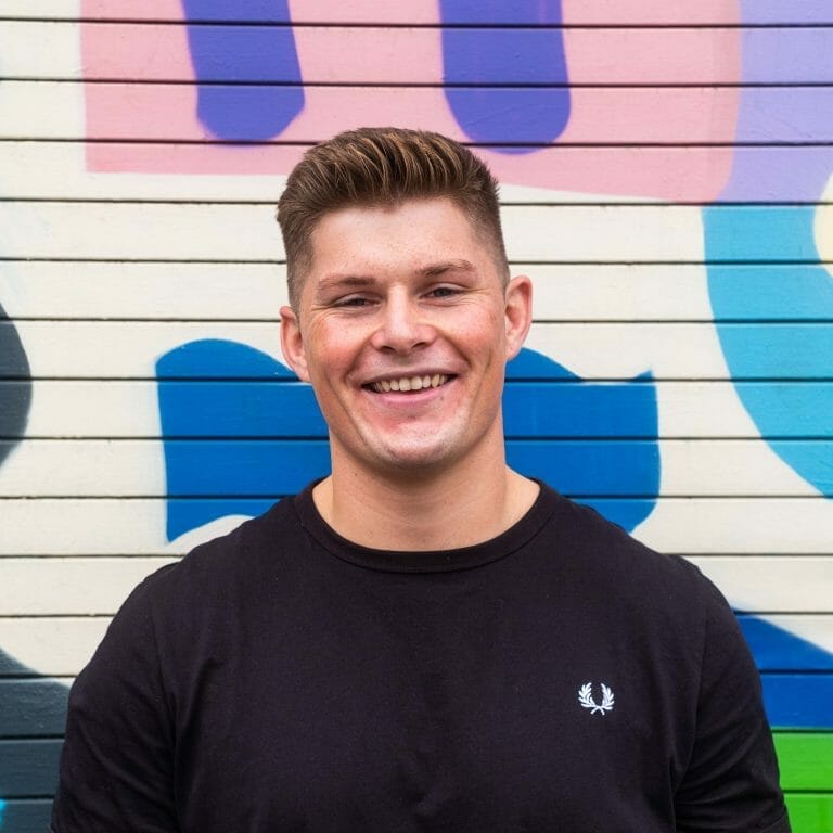 Smiling man in front of colorful graffiti wall background